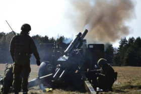 A towed 105 mm howitzer crew firing.